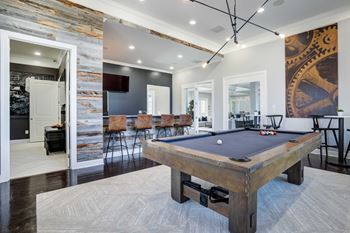 A pool table in a living room with a bar